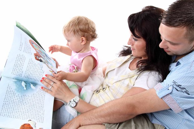 Eltern schauen mit ihrem Kleinkind ein Bilderbuch an.